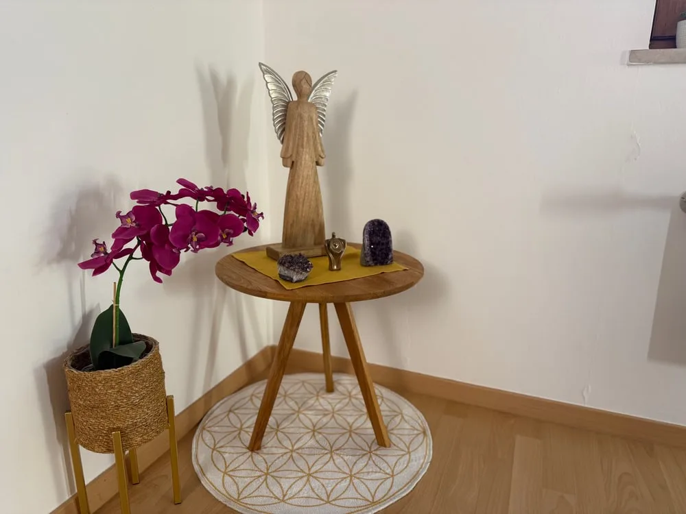 Holzengel, Orchidee und Kristalle auf einem runden Beistelltisch