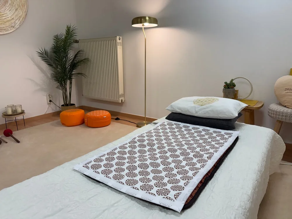Behandlungsraum mit Liege, Kissen, Stehlampe und Pflanzen